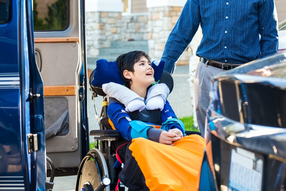 Special needs boy in wheelchair on vehicle handicap lift